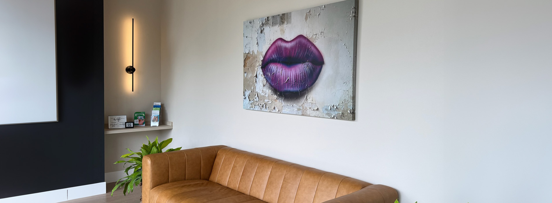 The image shows an interior space with a large, purple lip painting on the wall above a sofa, which has a modern design.
