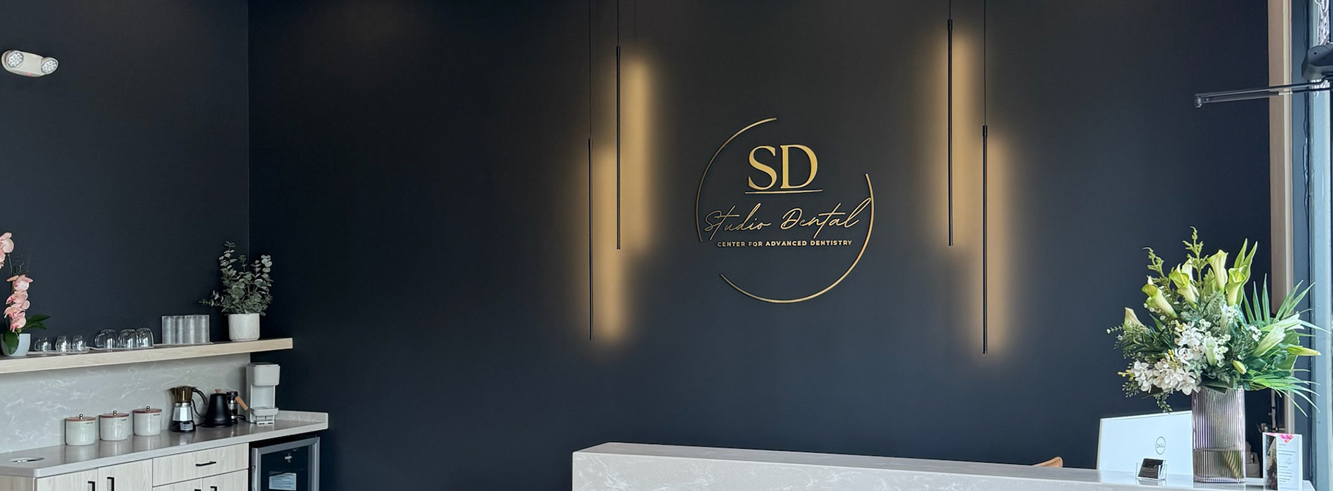 The image shows an interior space with a dark wall featuring illuminated signage for The Distillery and a logo, set against a backdrop of shelves stocked with bottles and a counter with a display case.