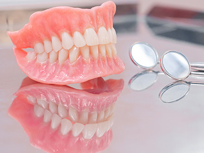 A photographic collage showing two images side by side  on the left, a close-up of an artificial red lip denture with visible teeth  on the right, a pair of metal tongs resting next to the denture.