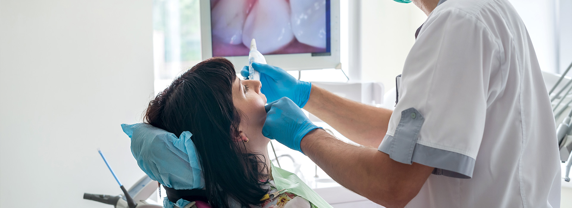 The image shows a healthcare professional performing dental work on a patient s teeth using dental instruments, with the patient seated in a dental chair.