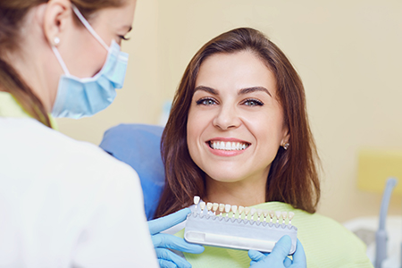 A dental hygienist with a smiling woman receiving teeth cleaning services.
