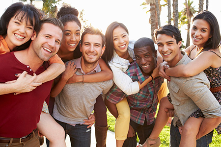 A group of people posing together outdoors for a photo, smiling and embracing each other.